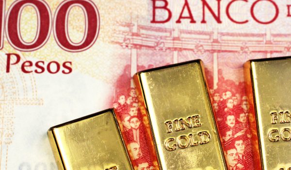 Three small gold bars up close in macro with a one hundred Mexic
